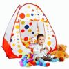 A realistic photo of a young child dressed as a doctor, holding a stethoscope while sitting in front of a colorful polka-dot play tent with a teddy bear and scattered toy balls. Little Doctor Playing with Colorful Tent and Teddy Bear